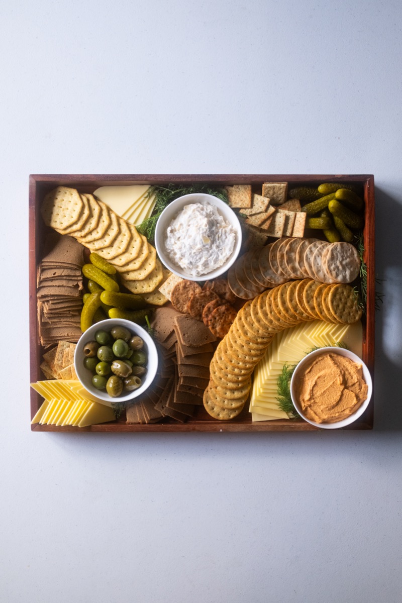 Cheese and cracker board with olives, dips, and pickles